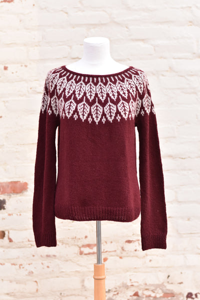 A burgundy sweater with grey leaves around the yoke