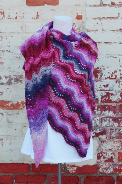 a colorful knitted shawl in shades of pink, purple, blue and red