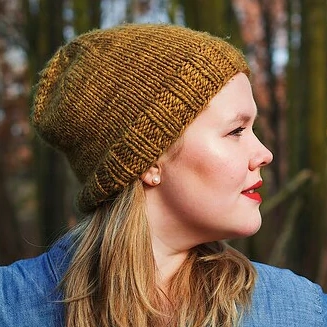 A blond woman with red lipstick wears a caramel colored knitted beanie