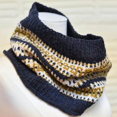 A navy blue, gold and cream patterned knitted cowl