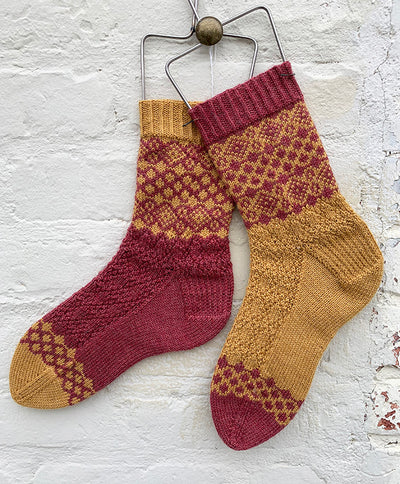 Two patterned socks in inverted colors of burgundy and gold