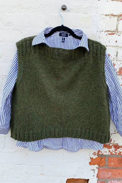 A dark green knitted vest is worn over a blue and white striped shirt